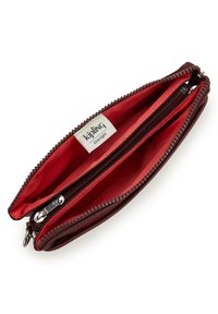 Billetera marrón con cremallera y un interior de tela roja que muestra múltiples compartimentos y una etiqueta blanca de la marca Kipling.