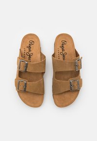 Rudos zomšiniai sandalai su dviem plačiais dirželiais ir sidabriniais sagtimis. Padas turi tekstūruotą paviršių su ženklu 'Pepe Jeans London'.