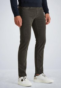 Slim-fit olijfgroene jeans gemaakt van katoen, met subtiele stiksels en een klassieke vijf-pocketdesign, gecombineerd met witte sneakers.