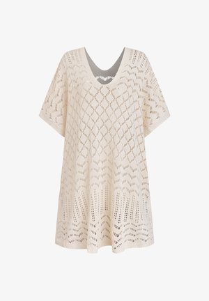 Poncho tricoté en crème avec un col en V, présentant un motif de losanges ajouré et des manches amples pour un ajustement décontracté. Texture douce.