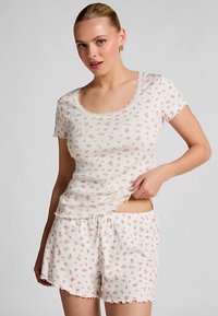 Katoenen pyjamaset met bloemenprint, bestaande uit een top met korte mouwen en een ronde halslijn, en een short met een elastische tailleband en gegolfde randen.
