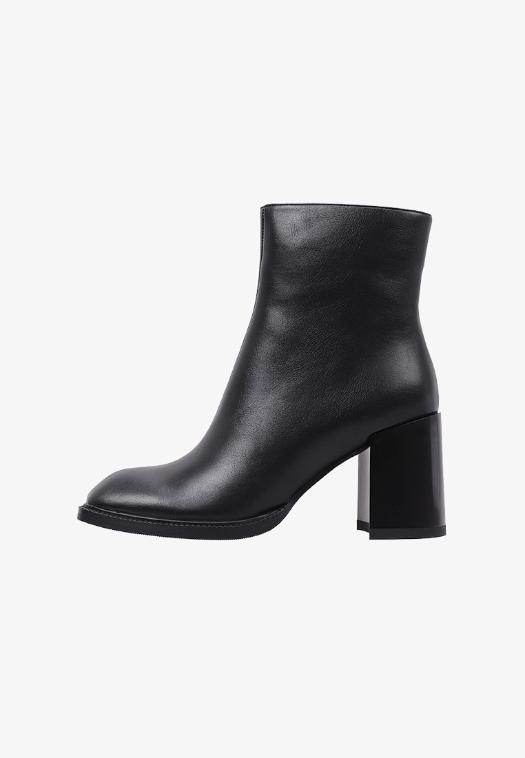 Botín de cuero negro hasta el tobillo con punta redondeada, textura suave y tacón bloque transparente y voluminoso. Diseño minimalista sin acentos visibles.