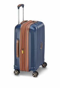 Valigia rigida di colore blu navy con dettagli marroni. Presenta una superficie texturizzata, manico telescopico e quattro ruote per una facile mobilità.