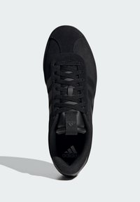 Crne sportske cipele s nubuk gornjim dijelom, sa tri crne pruge, okruglim vezicama i teksturiranom potplatom. adidas logo blizu pete.