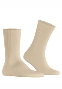 Beige Baumwollsocken mit gerippter Struktur, mittlerer Wadenhöhe, nahtlosem Zehenbereich und dezenten orangefarbenen Akzenten an der Sohle.