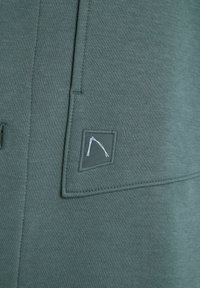 Groene sweatshirt met een patch pocket met een bergafbeelding, gemaakt van zachte stof met een gladde textuur en nette naden.