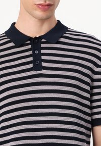 Stribet polo t-shirt med vekslende marineblå og lysegrå striber, en mørk marineblå krave, og tre-knaps lukning. Strikket tekstur.