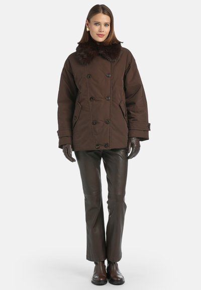 Bruine dubbele-geknoopte jas met een nepbontkraag, gecombineerd met bruine leren broeken en handschoenen, met een relaxte pasvorm en knopenaccenten.