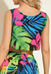 Crop top wykonany z lekkiego materiału z żywym tropikalnym wzorem, który prezentuje duże zielone liście palmowe oraz różowe akcenty. Okrągły dekolt, bez rękawów.