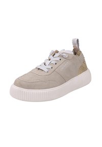 Beżowy zamszowy sneaker z białą grubą podeszwą, białymi sznurowadłami oraz wzorzystą beżowo-złotą zawieszką na pięcie. Nazwa marki na bocznym panelu.