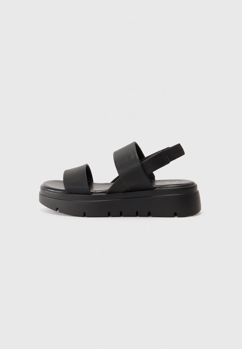 Sorte sandaler med to brede stropper, en tyk såle og en teksturert overflate. Justerbar hælstropp og et minimalistisk design.