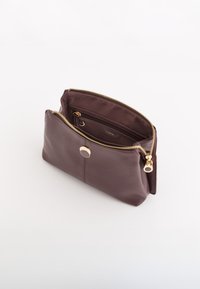 Brązowa skórzana sakiewka z złotym zamkiem błyskawicznym i elementami, z gładką powierzchnią na zewnątrz i wyściełanym tkaniną wnętrzem, o sztywnym prostokątnym kształcie.