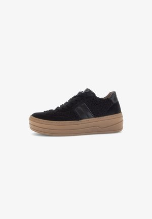 Zwarte sneaker met een gestructureerde bovenkant, suede en nepbont materialen, vetersluiting en een dikke, tan rubberen zool. Beschikt over zwarte leren accenten.