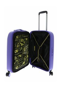 Valise rigide violette avec un intérieur noir ornée de motifs jaunes. Poignée rétractable et roulettes pour la mobilité.