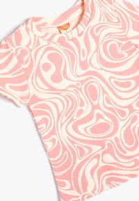 Kortærmet baby t-shirt lavet af ribbet stof, med et pink og creme farvet abstrakt svirl mønster. Rund halsudskæring, blød tekstur.
