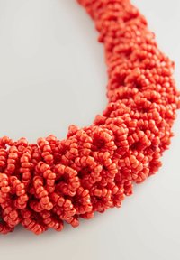 Collar de cuentas rojas con cuentas redondas brillantes en un diseño texturizado y agrupado, creando una apariencia gruesa y volumétrica.