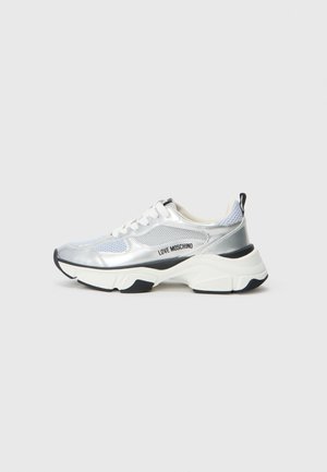 Silver and mesh sneaker with a chunky white sole and black accents. Features logo on the side, round laces, and textured design.