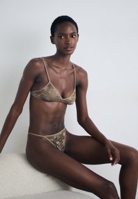 Camouflage-patterned bikini in beige tones. Features a triangular bra with thin straps and matching thong with logo detail.