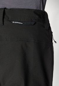 Svarte bukser laget av glatt stoff med rett form. Har et merkelapp med "Didriksons" logo, elastisk midjebånd og minimale design detaljer.