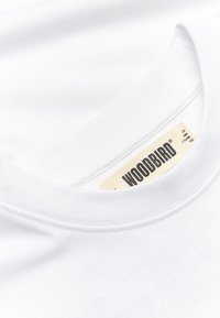 Λευκό T-shirt με στρογγυλή λαιμόκοψη και υφαντή ετικέτα της μάρκας WOODBIRD ραμμένη στην εσωτερική πλευρά του γιακά.