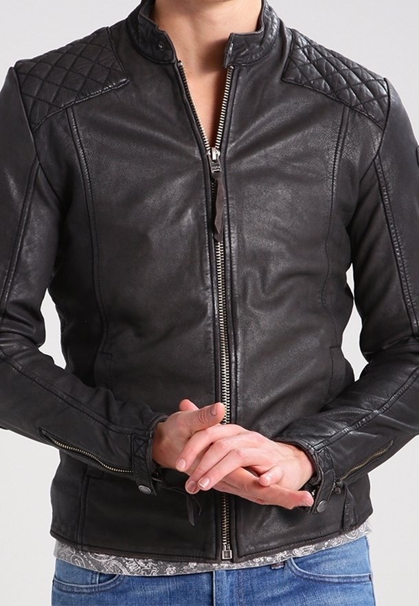 Giacca in pelle nera con design trapuntato sulle spalle, collo alto e cerniere frontali e sui polsini. Vestibilità slim con dettagli sottili.