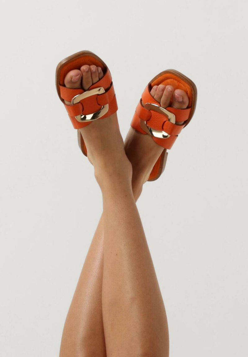Oranje slide slippers met een gladde leren afwerking, grote metallic gespen en een gestapelde houten hak. Open teen ontwerp.