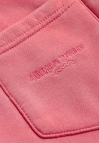 Różowa tkanina o teksturowanej powierzchni, z haftowanym logo w jaśniejszym odcieniu różu. Projekt zawiera kieszeń z detalem przeszycia.