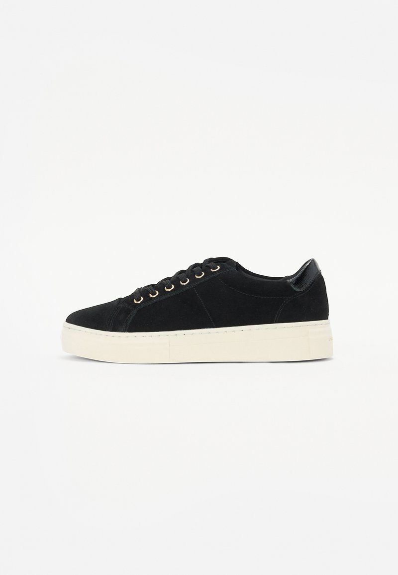 Sneaker in camoscio nero con superficie texturizzata, suola in gomma bianca e occhietti dorati. Presenta un accento lucido nero sul tallone.