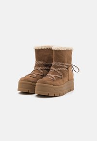 Bottes de cheville en suède marron avec une doublure en fourrure douce, une semelle épaisse et des lacets contrastés. Présente une surface texturée et un bout rond.