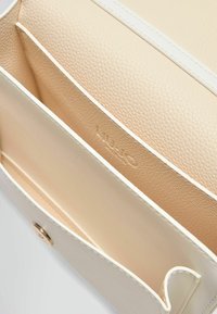 Lys beige lædertaske indvendig med to rum, en struktureret overflade, hvid syning og en guld trykknaplukning.
