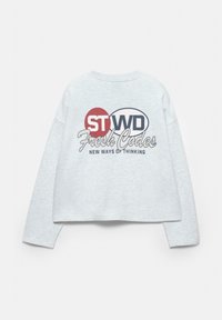 Grå, langærmet cropped sweatshirt med et trykt design med teksten "STWD Fresh Codes" og en rød cirkel akcent. Blød tekstur.
