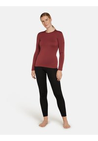 Långärmad, figurnära topp i burugundytyg med rund halsringning. Svarta, stretchiga leggings. Slinky textur, minimalistisch design.