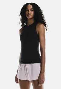 Black sleeveless top made of stretchy fabric, paired with light pink shorts. The top has a fitted design with a round neckline.