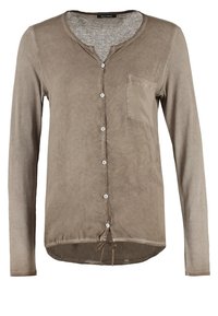 Chemise taupe à manches longues avec boutons, encolure ronde, poche poitrine à gauche et ourlet avec cordon de serrage ajustable.