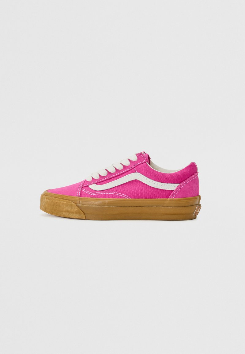 Pink canvas sneaker with white accents, featuring a rounded toe, flat lace-up design, and gum rubber sole. White stitching details visible.