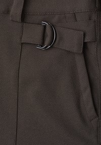 Close-up of dark fabric with fine diagonal stripes and a black metal D-ring attached to a fabric belt loop.