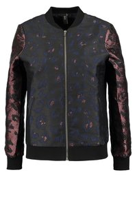 Svart bomberjacka med texturerat, marinblå leopardtryck och glänsande burgunderärmar. Har en frontdragkedja samt ribbade muddar och nederkant.