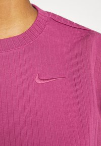 Rosa ribbat tröja med rund halsringning, med en tonad broderad Nike swoosh på bröstet. Mjuk textur och figurnära design.