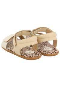 Sandalias beige con una tira brillosa, cierre de velcro y plantilla de estampado de leopardo. Material suave y diseño de suela plana para mayor comodidad.