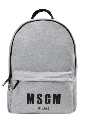 Henkilö, jolla on päällään beigenväriset käännetyt housut, mustat juhlakengät, tummansininen neule ja suuri vaaleanharmaa reppu, jossa MSGM-logo.
