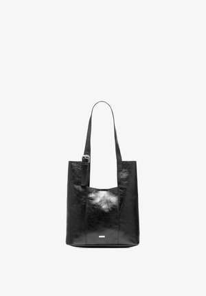 Czarna skórzana torba tote z regulowanym paskiem na ramię i srebrną klamrą, minimalistyczny design, stojąca w pionie na białym tle.