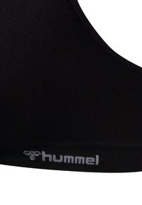 Zwarte geribbelde sportbeha met een ronde halslijn. Bevat een contrasterend wit "hummel"-logo langs de onderband. Zachte stoftextuur.