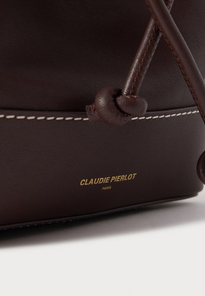 Hnedá kožená kabelka v tvare vedra s bielym prešitím, vybavená sťahovacou šnúrkou a detailom zlatého vyrazeného loga pri spodnej časti.