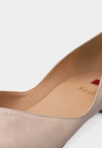 Chaussure pour femme à talon bas en suède beige avec intérieur en cuir lisse et bout arrondi, conçue pour des occasions formelles ou un usage au bureau.