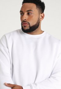 Witte sweatshirt met een ronde halslijn en lange mouwen, voorzien van een zachte textuur en een ontspannen pasvorm. Geen zichtbare patronen of accenten.