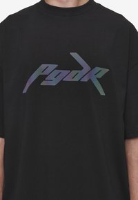 Black t-shirt made of cotton, featuring a large, reflective, multicolored text logo "Pgdr" across the chest in a modern font.