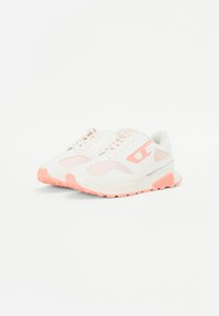 White sneakers featuring pink accents, mesh panels, and a textured sole. Includes laces and a cushioned, supportive design.