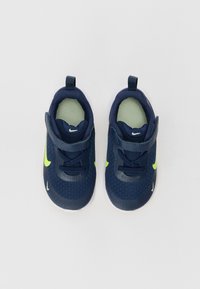 Marineblaue Sneaker mit einem strukturierten Mesh-Obermaterial, limegrünen Akzenten und weißen Sohlen. Verfügt über einen Klettverschluss und eine Zuglasche für ein einfaches Anziehen.