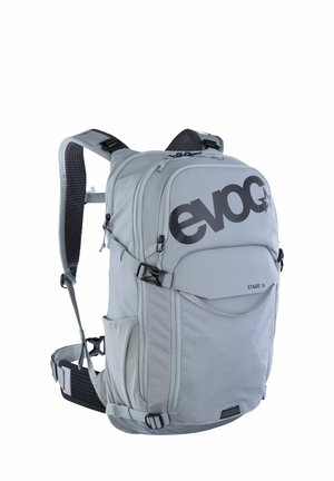 Gray backpack with a glossy black logo, featuring padded shoulder straps, side pockets, and adjustable compression straps for support.
