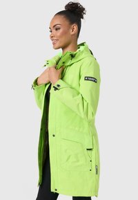 Groene waterdichte jas met een capuchon, meerdere zakken, ritsen en logodetails. Slim fit met verstelbare elementen. Gladde textuur.